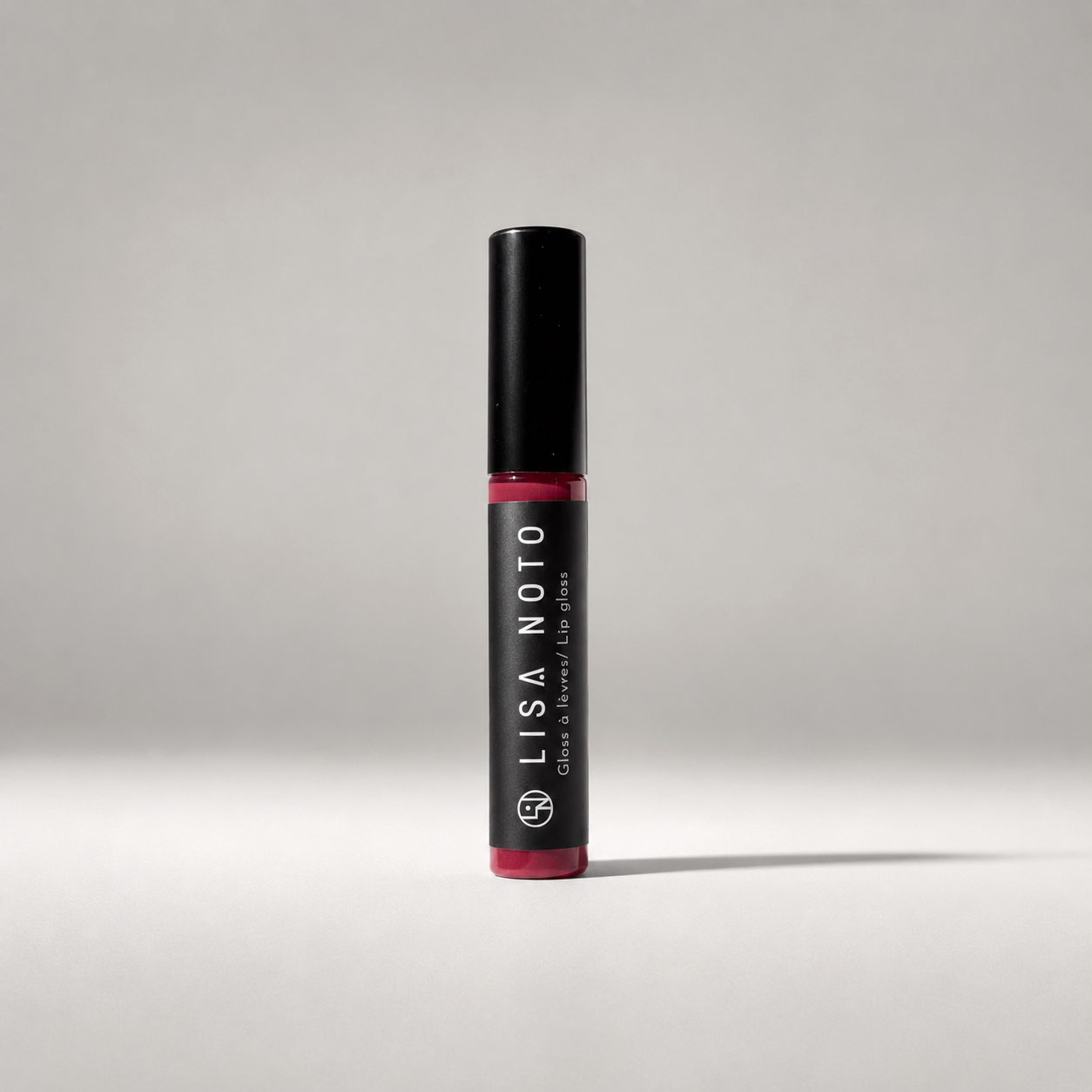 velvet Cherry lip gloss by Lisa Noto on a light neutral grey background, clean high-end e-commerce image with soft luminous light.