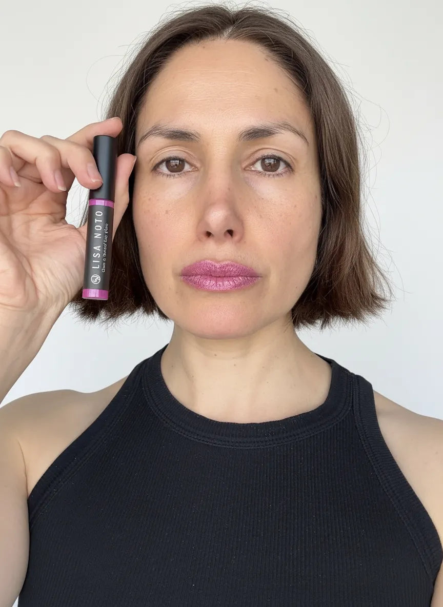 Model holding Lisa Noto metallic lilac hydrating lip gloss, elegant natural beauty look with soft daylight and refined minimalist aesthetic.