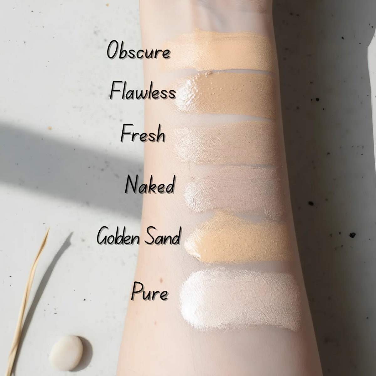 Swatches des 6 teintes du cache-cernes crème Lisa Noto sur bras — Obscure, Flawless, Fresh, Naked, Golden Sand, Pure